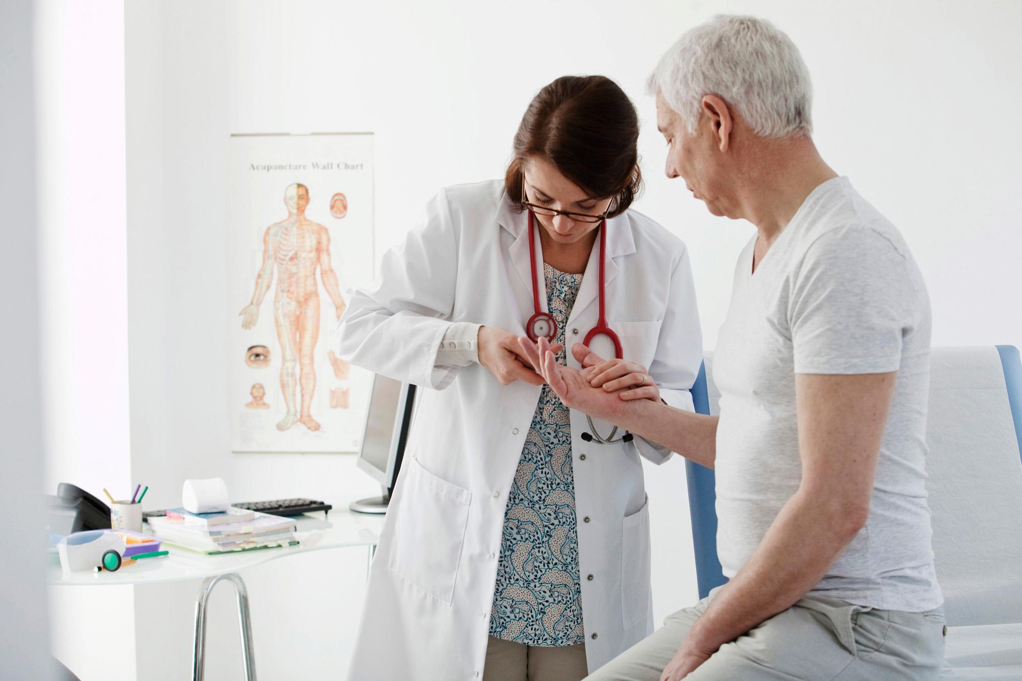 rhumatologue qui analyse les mains d\'un patient homme
